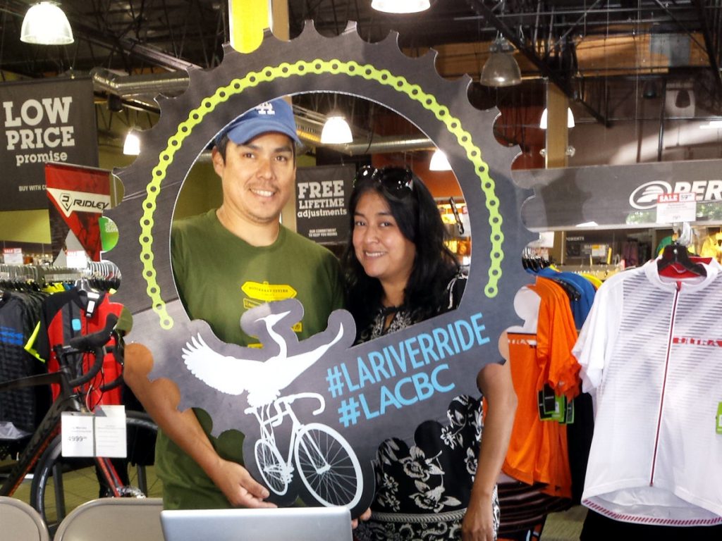Adrian Oviedo and Sandy Brambila pose with the LACBC River Ride logo at Performance Bike in Long Beach